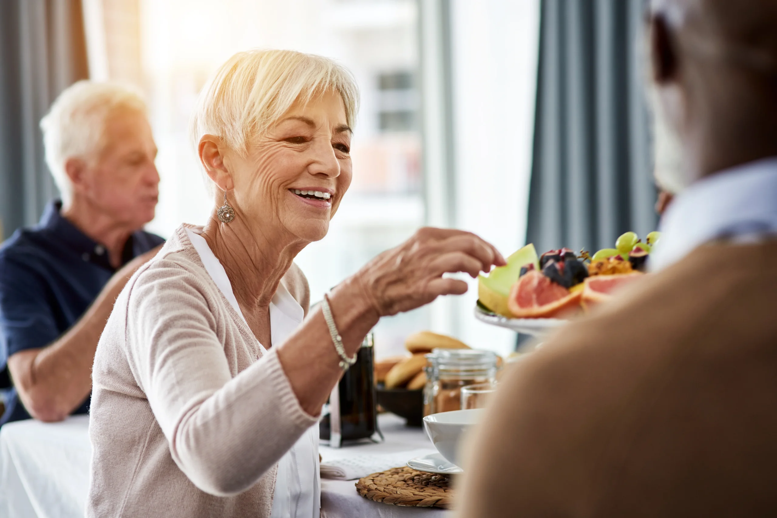 senior woman choosing fruit from fruit tray